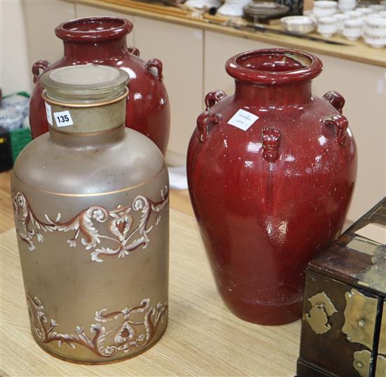 A Victorian black painted opaque glass jar and cover, together with a pair of red glazed terracotta vase, 46cm (3)